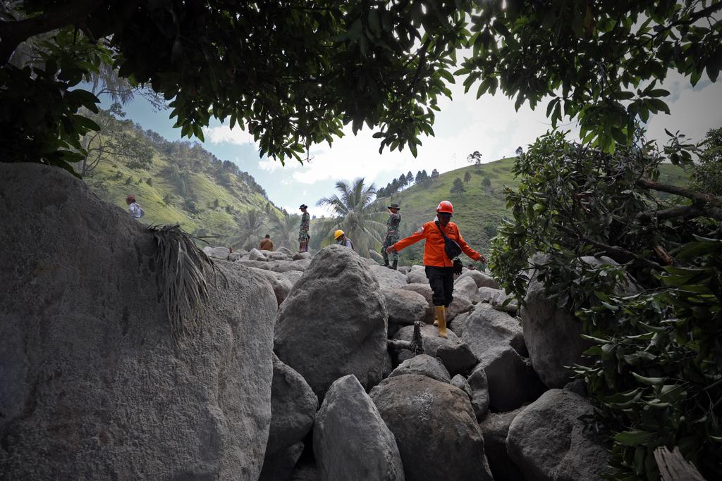 Petugas dari BPBD berjalan di atas bebatuan besar yang menumpuk atas peristiwa banjir bandang dan tanah longsor di Humbang Hasundutan, Sumatera Utara, Senin (4/12).